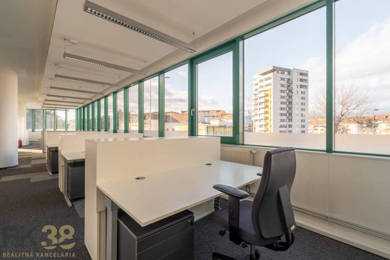 Prostorné kanceláře s otevřenými boxy a velkými okny s výhledem na město.