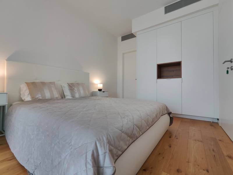 Ložnice s manželskou postelí, šatní skříní a podlahou s dřevěným dekorem v 2pokojovém bytě.