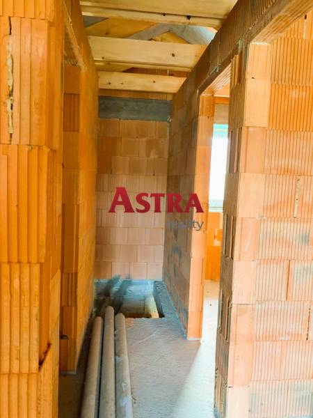 Interiér s cihlovými zdmi, dřevěným stropem a položenými trubkami v nové chatě.