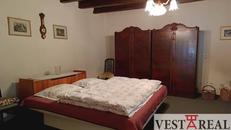 Ložnice v rodinném domě s postelí, vestavěnou skříní a venkovským dekorem.