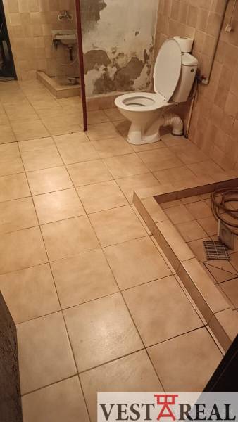 Koupelna v rodinném domě s obklady a toaletou, jednoduchý a úsporný design.