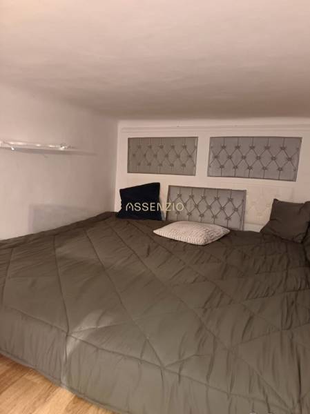 Ložnice v 3pokojovém bytě s nízkým stropem, pukovými panely na stěně a podlahou s dřevěným dekorem.