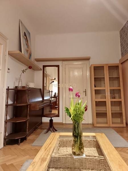 Interiér 3-pokojového bytu se stolem, vázou s květinami a dřevěným dekorem podlahy.