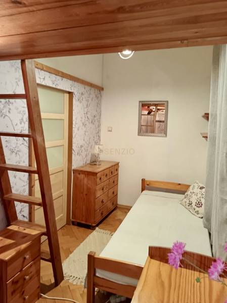 Pokoj se schody, dřevěným stropem, nábytkem a podlahou s dřevěným dekorem.