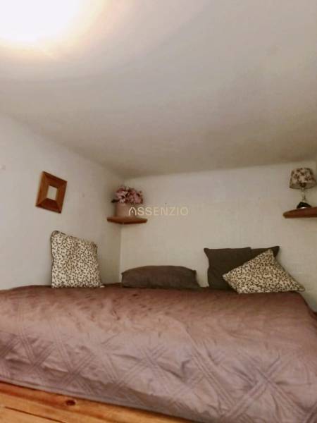 Ložnice ve 3-pokojovém bytě s dekorativními polštáři a noční lampou na poličce.