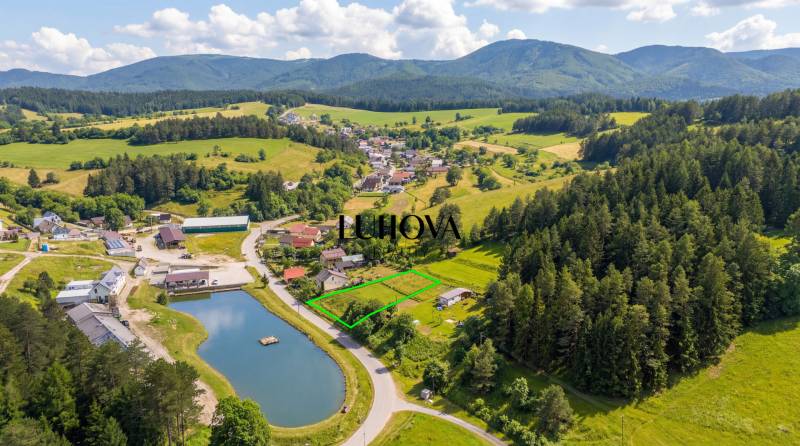 Letecký pohled na pozemky - bydlení v Ďurďovém, Považská Bystrica obklopené lesy a jezerem.