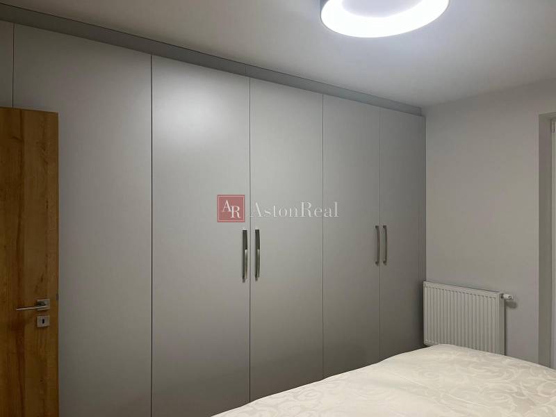 Ve 3pokojovém bytě jsou šatní skříně s bílými posuvnými dveřmi a postelí.