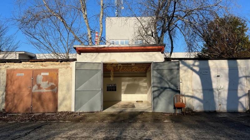 Garáž na Agátové ulici v Bratislavě - Dúbravce s plechovými dveřmi a židlí venku.