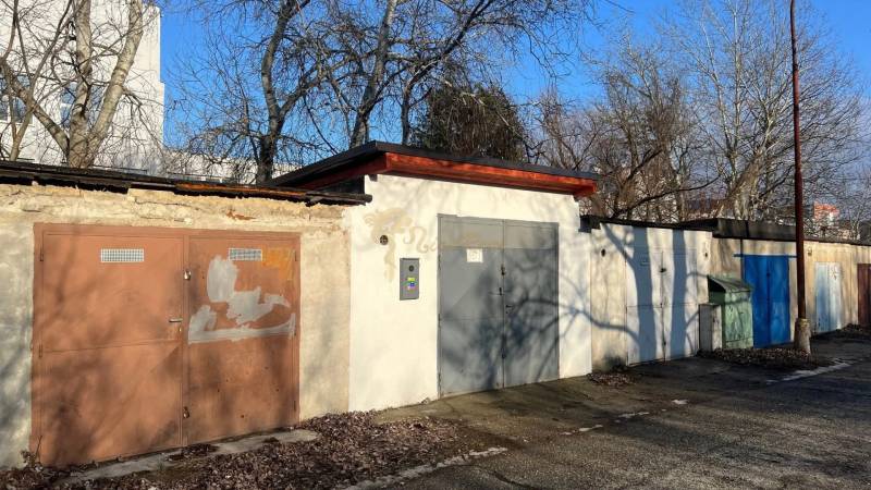 Různobarevné garáže na Agátové ulici v Bratislavě - Dúbravce obklopené stromy.