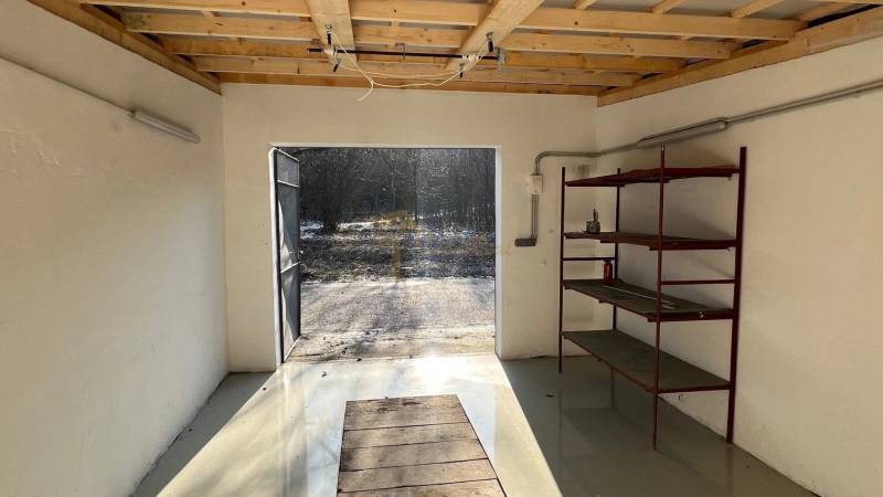 Garáže na Agátové ulici v Bratislavě-Dúbravce se železnými policemi a otevřenými dveřmi.