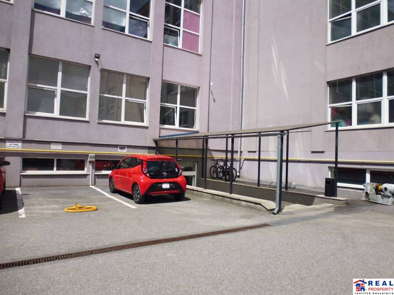 Parkoviště na Masarykově ulici v Prešově s cyklistickým stojanem u kanceláří.