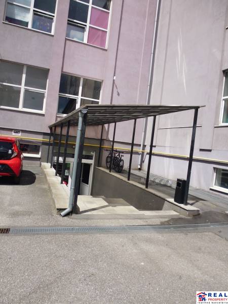 Budova kanceláří na Masarykově ulici v Prešově s přístřeškem a parkovištěm.