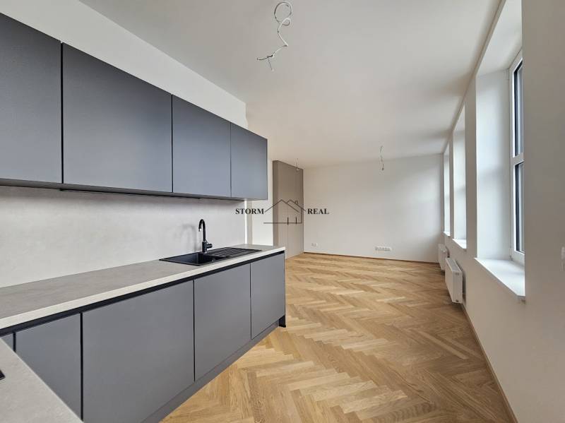 Kuchyně v 1-pokojovém bytě s podlahou s dřevěným dekorem a velkými okny.