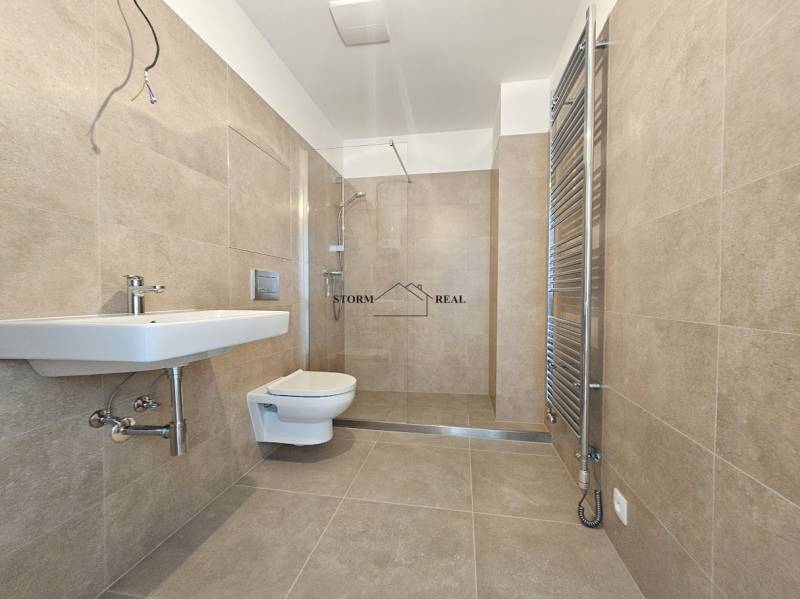 Koupelna s keramickými obklady, závěsným WC a sprchovým koutem v 1-pokojovém bytě.