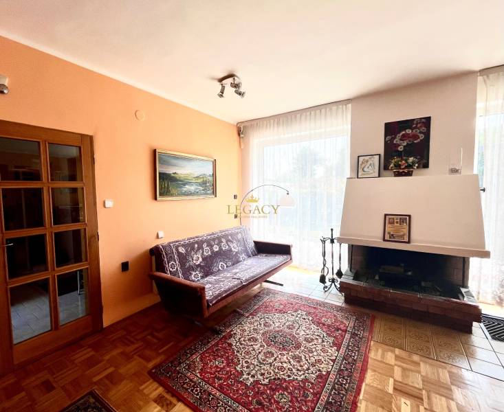 Obývací pokoj v rodinném domě s krbem, pohovkou a podlahou s dřevěným dekorem.