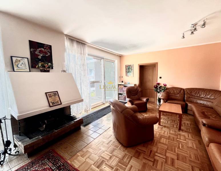 Rodinný dům s krbem, pohovkami, obrázky na stěně a podlahou s dřevěným dekorem.