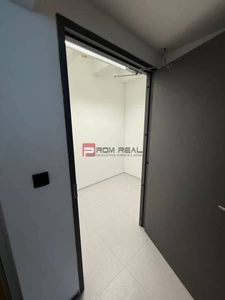 Otevřené dveře vedoucí do prázdné místnosti s bílými stěnami v kancelářích.