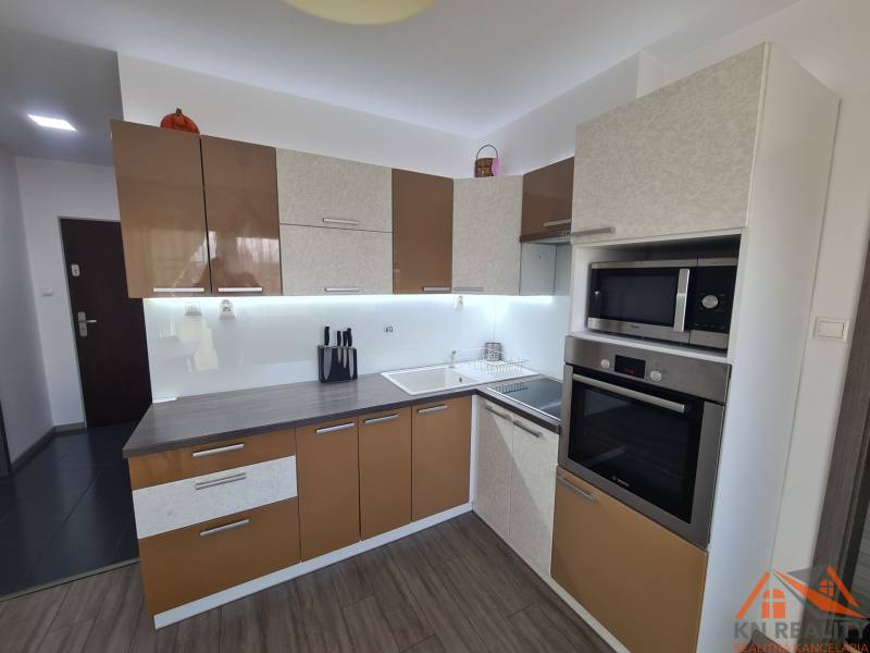 Kuchyně 2pokojového bytu s podlahou s dřevěným dekorem a moderními spotřebiči.