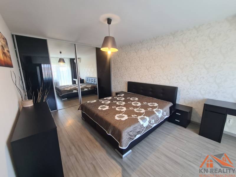 Ložnice v 2-pokojovém bytě s velkou postelí a podlahou s dřevěným dekorem.