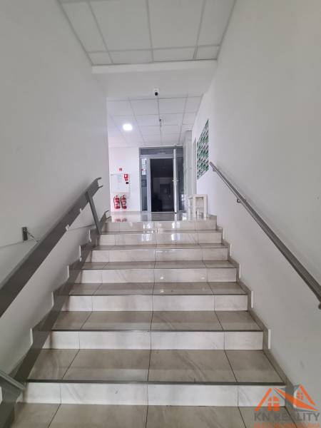 Schodiště s bílými stěnami a dlaždicovou podlahou vede do vstupu v 2-pokojovém bytě.