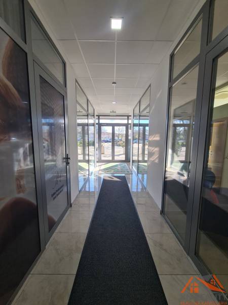 Světlá chodba se skleněnými dveřmi a mramorovou podlahou v Komárně, vhodná pro 2-pokojový byt.