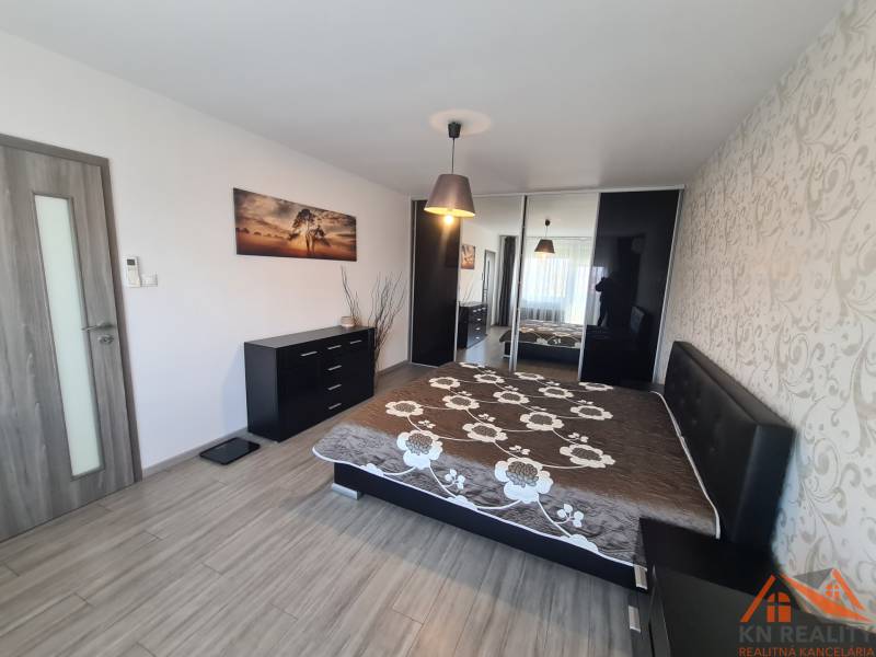 Ložnice v 2pokojovém bytě s podlahou s dřevěným dekorem a vestavěnou skříní.