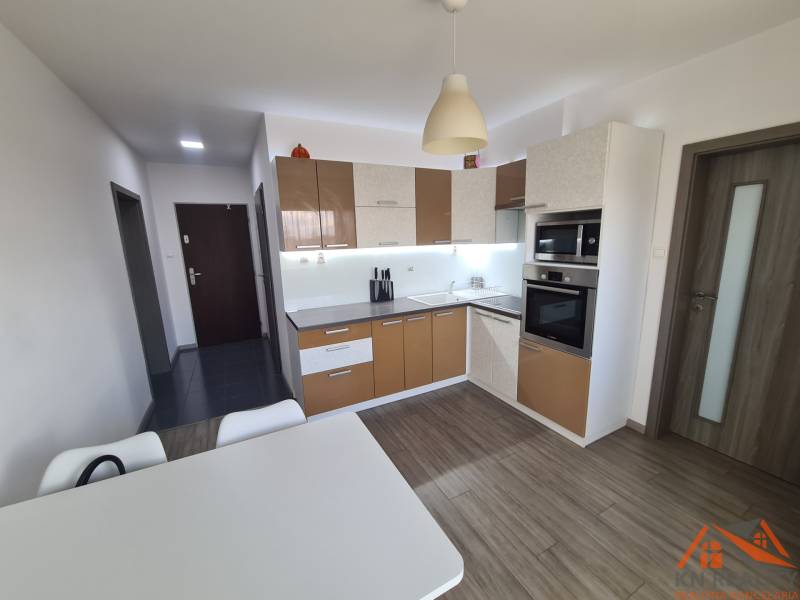 Kuchyně se spotřebiči a stolem, podlaha s dřevěným dekorem v 2pokojovém bytě.