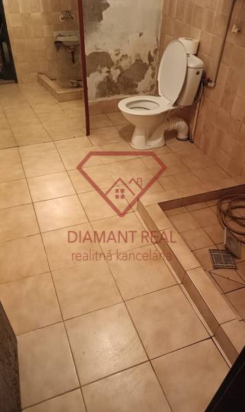 Koupelna v rodinném domě s toaletou, umyvadlem a dlažbou na zemi.