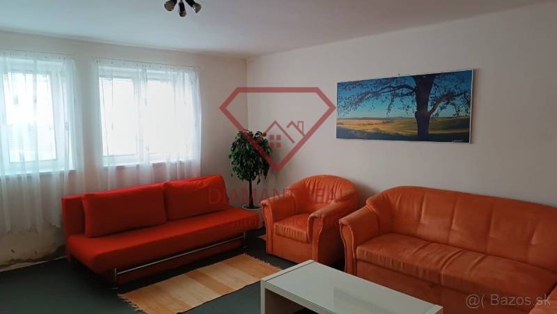 Obývací pokoj v rodinném domě s oranžovou sedačkou, křesly a obrazem krajiny.