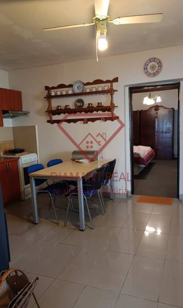 Jídelní kout a kuchyň v rodinném domě s poličkou a stropním ventilátorem.