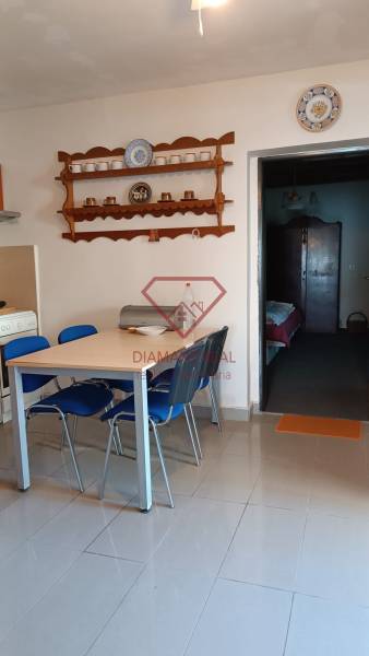 Jídelna rodinného domu s policemi na nádobí a stolem s modrými židlemi.