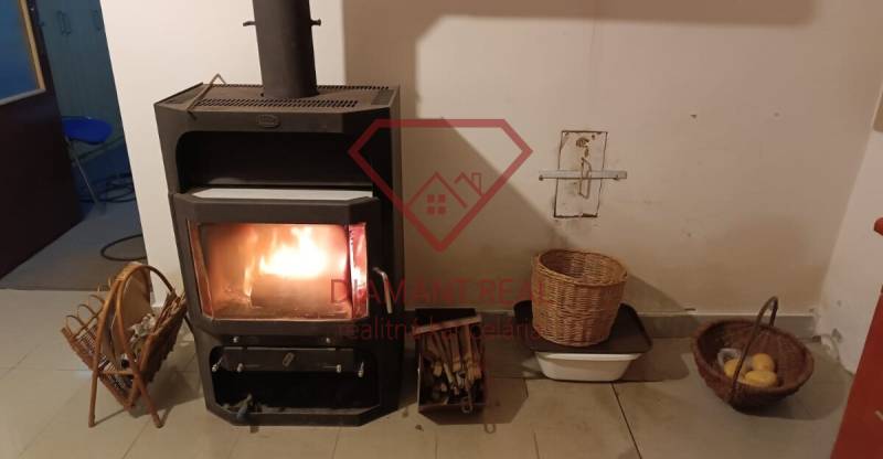 Krbová kamna v rodinném domě, vedle kterých jsou košíky s dřevem a ovocem.