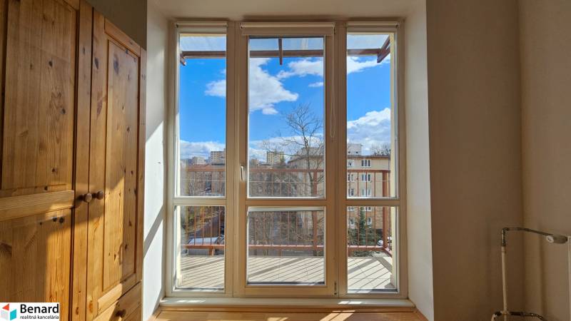 Pokoj s vestavěnou skříní a velkým oknem s výhledem na balkon.