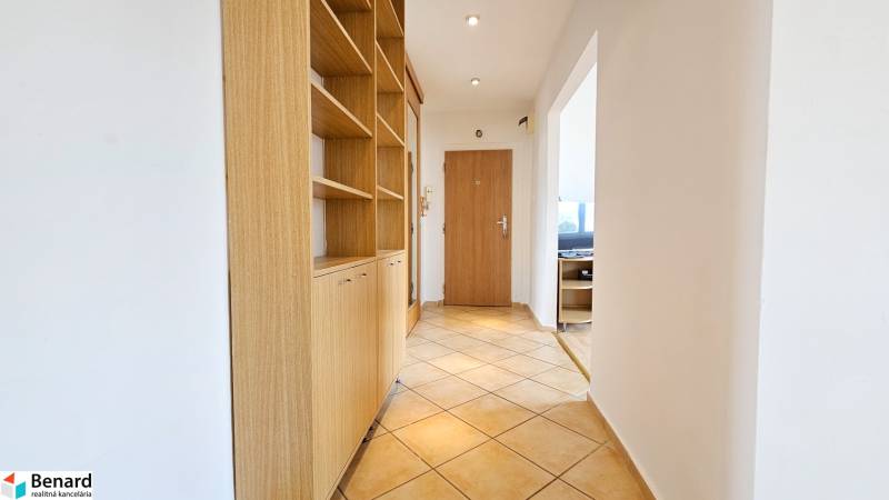 Chodba v 2-pokojovém bytě s vestavěnou skříní a světlou dlažbou.