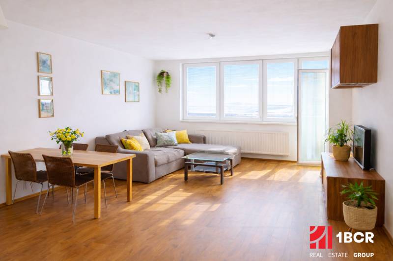 Obývací pokoj v 2-pokojovém bytě s rohovou pohovkou a podlahou s dřevěným dekorem.