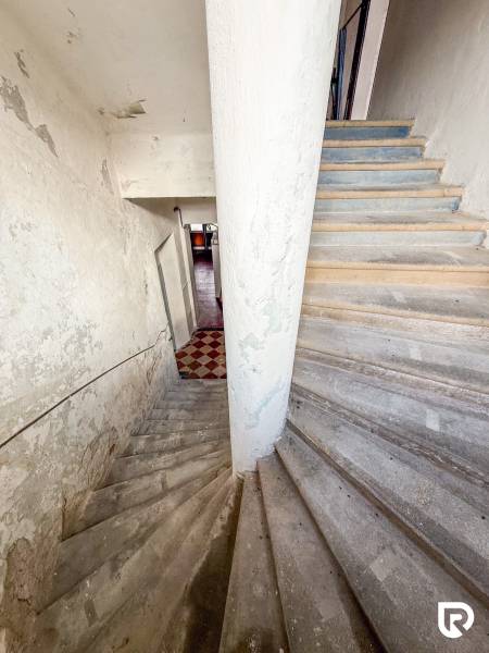 Schodiště vedoucí do interiéru rodinného domu s opotřebovanou omítkou na stěnách.