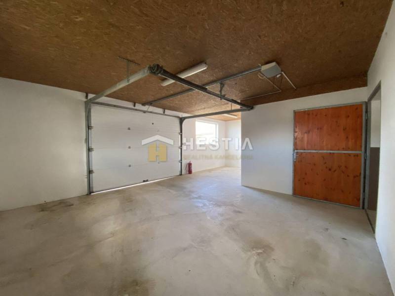 Sklady a haly s betonovou podlahou, dřevěným stropem a velkými garážovými vraty.