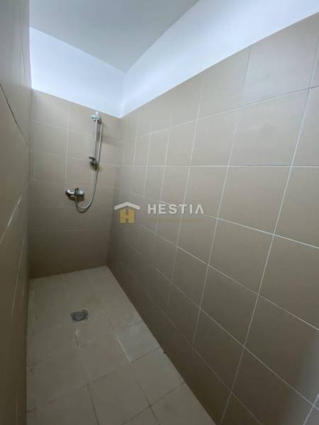 Sprchový kout s béžovými dlaždicemi v průmyslové hale.