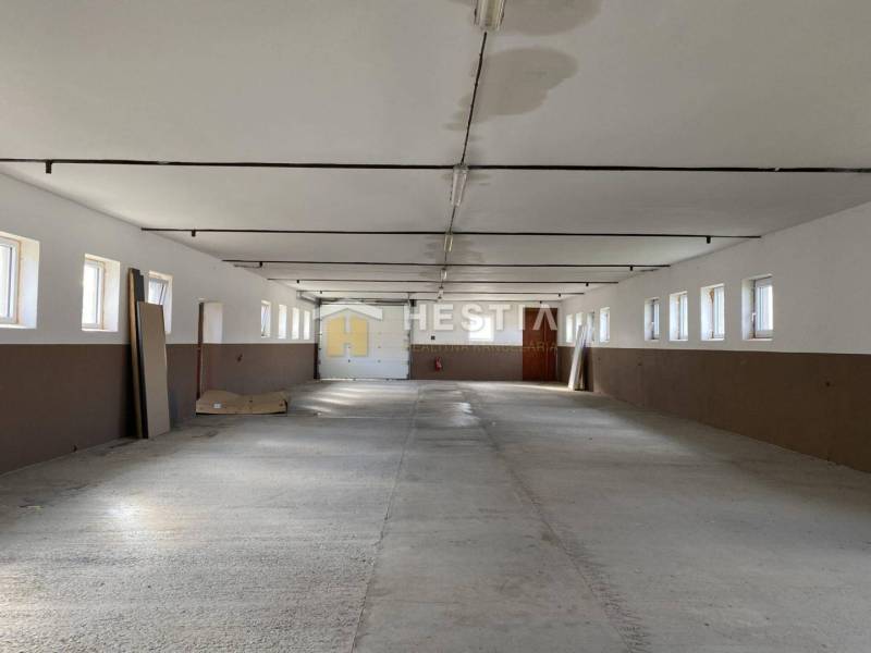 Rozsáhlý prostor ve skladech a halách s řadou oken a betonovou podlahou.