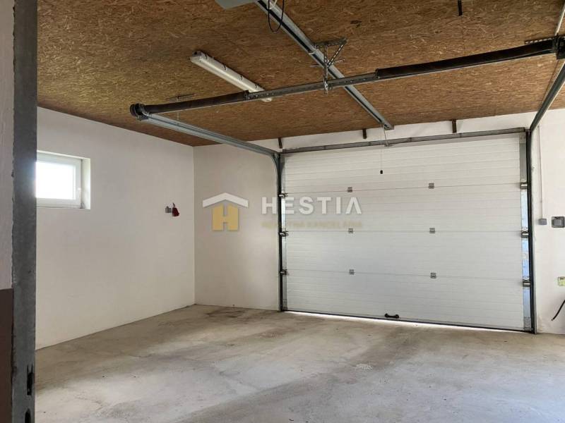 Interiér skladů a hal s garážovými vraty a betonovou podlahou.