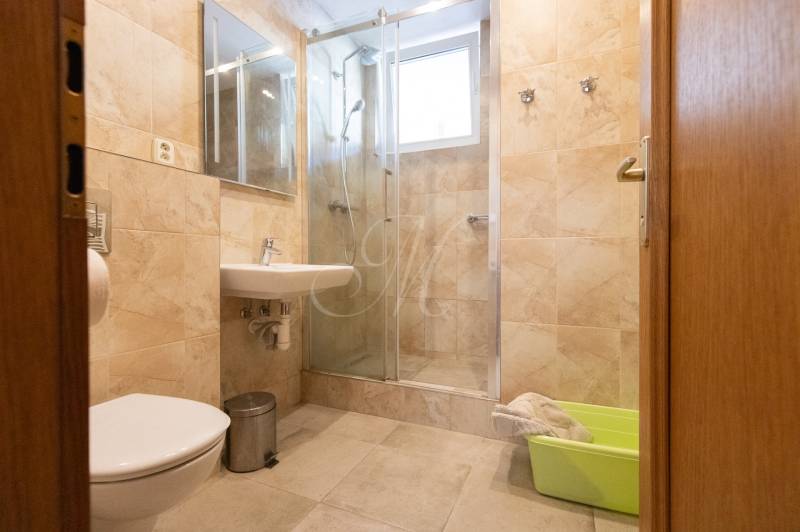 Koupelna v 3-pokojovém bytě s keramickými obklady a sprchovým koutem.