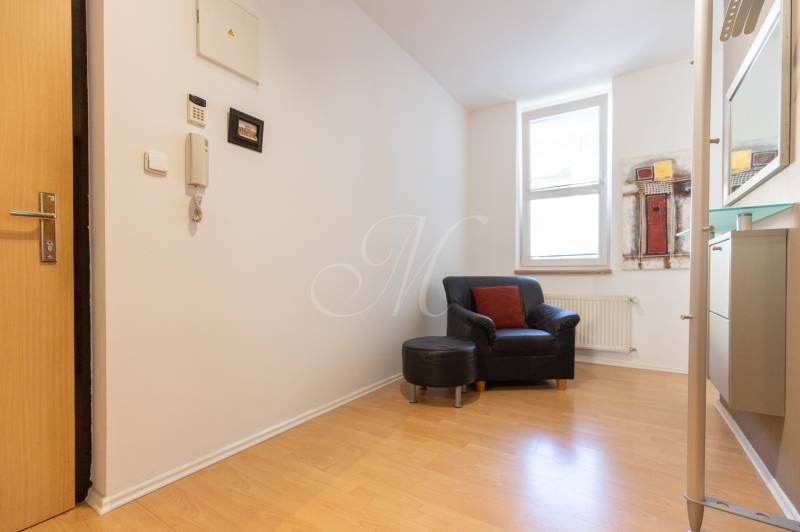 Interiér 3-pokojového bytu s křeslem, podlahou s dřevěným dekorem a obrazem na stěně.