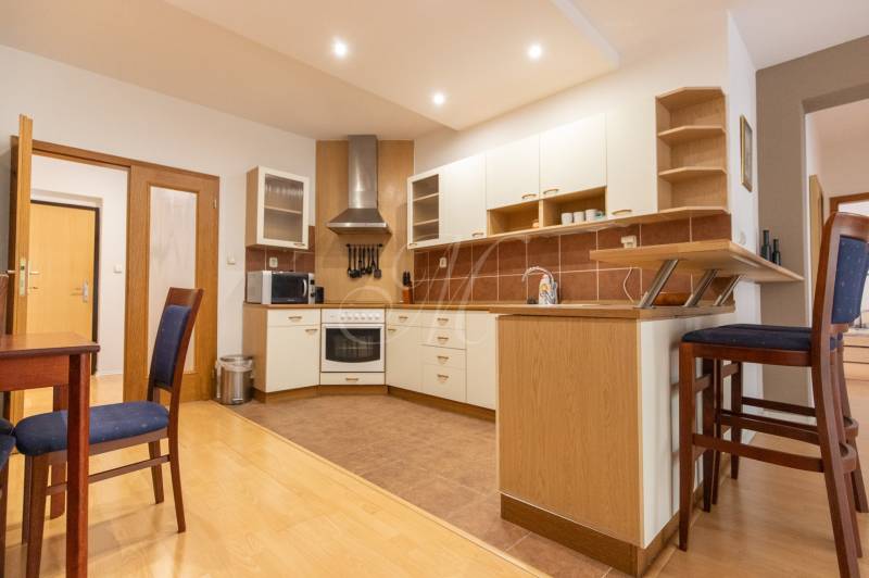 Kuchyně ve 3-pokojovém bytě s podlahou s dřevěným dekorem a barovým pultem.