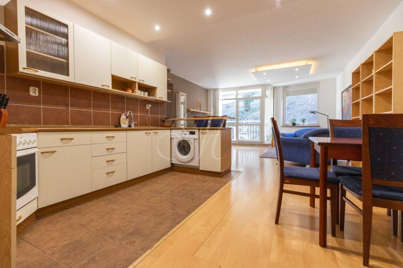 Kuchyně s podlahou s dřevěným dekorem, pračkou a jídelním stolem ve 3-pokojovém bytě.