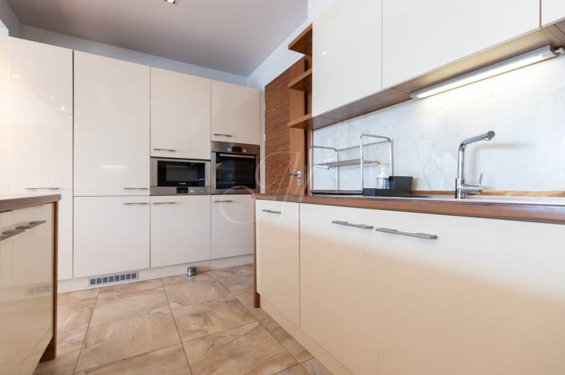 Kuchyně v 2-pokojovém bytě s bílými skříňkami a spotřebiči.