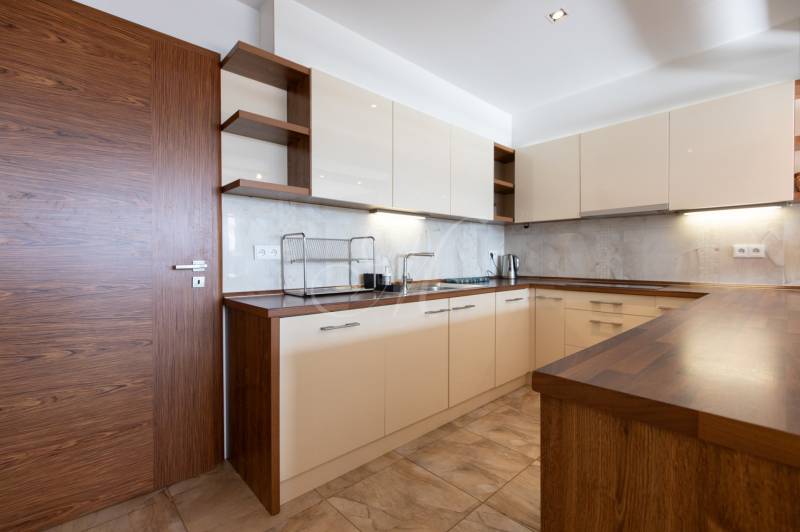 Kuchyně v 2-pokojovém bytě se světlými skříňkami a podlahou s dřevěným dekorem.