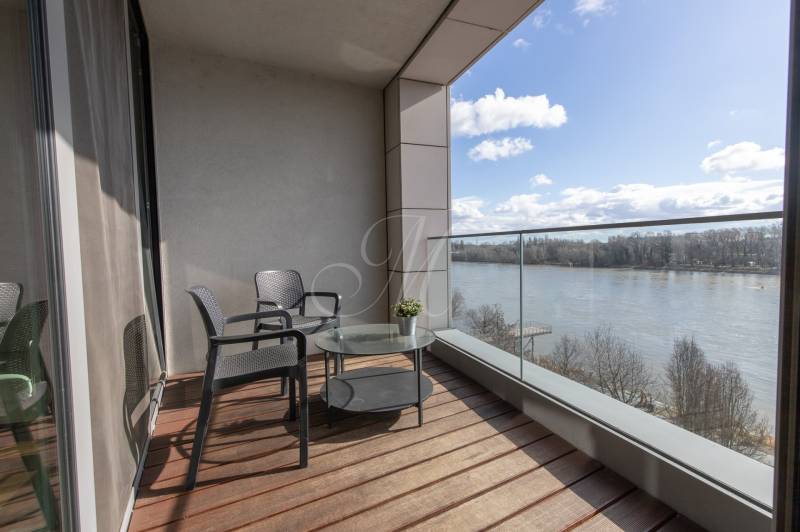 Balkon v 2-pokojovém bytě s výhledem na řeku, podlaha s dřevěným dekorem.