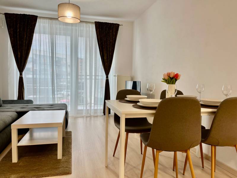 2-pokojový byt s podlahou s dřevěným dekorem, jídelním stolem a pohovkou.