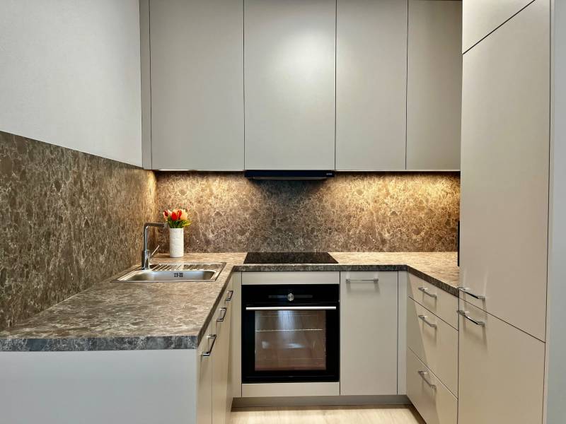 Kuchyně v 2pokojovém bytě s květinami, mramorovým obkladem a spotřebiči.