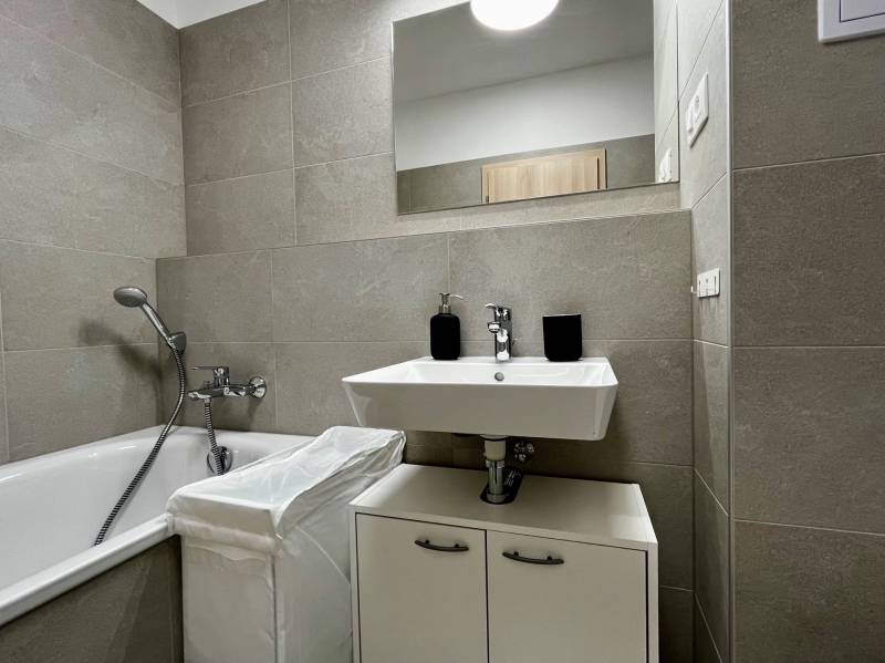 Koupelna s vanou a umyvadlem v 2pokojovém bytě s keramickými obklady.